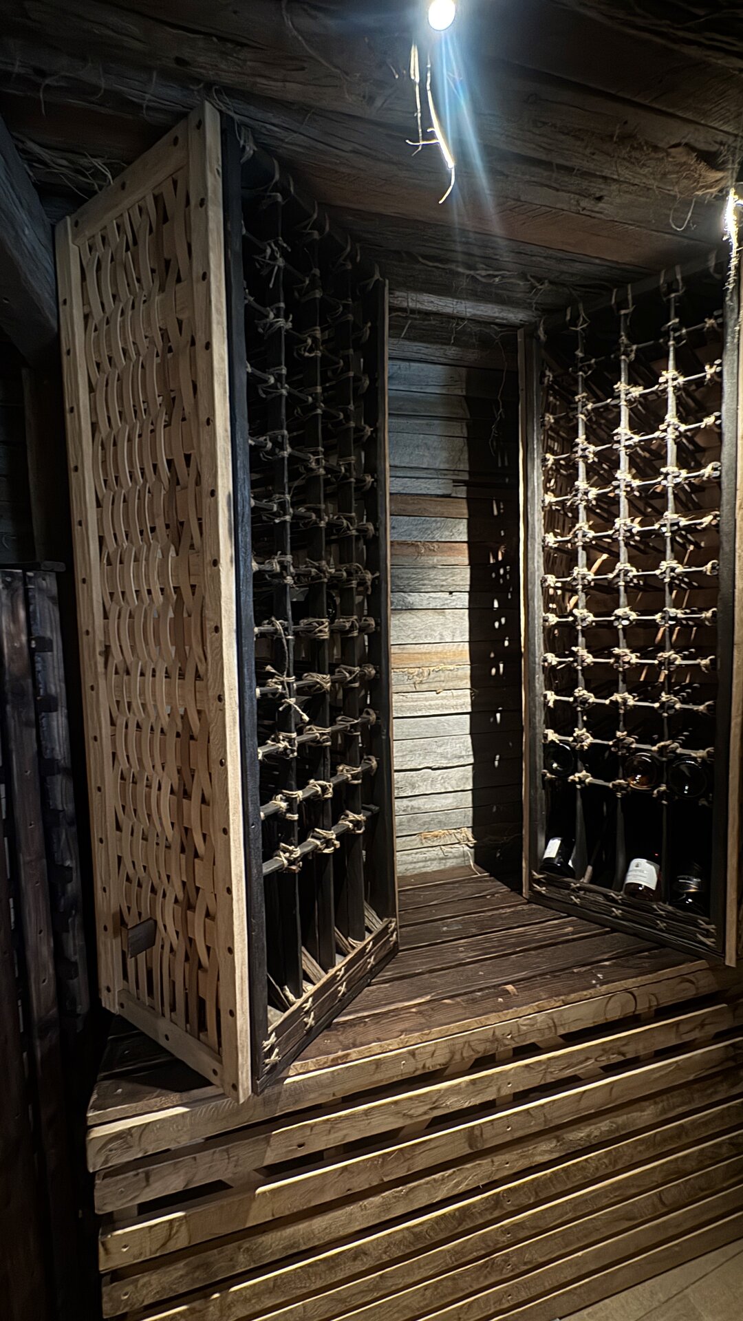 The wine racks — bentwood lattice, charred posts, jute-bound joinery